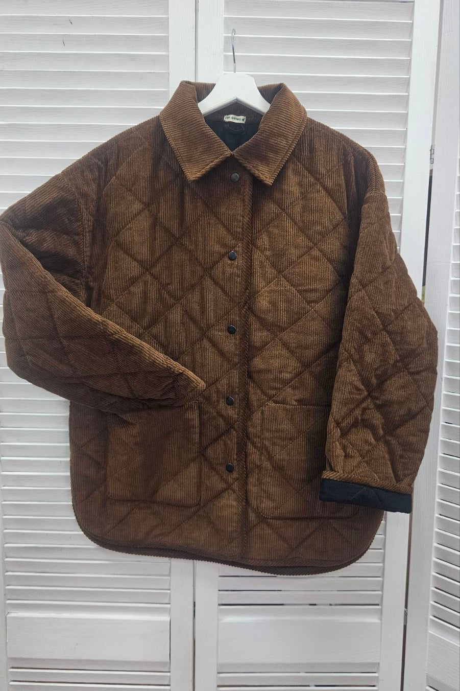 Sustainable women’s outerwear look with quilted corduroy jacket in natural tones, styled outdoors