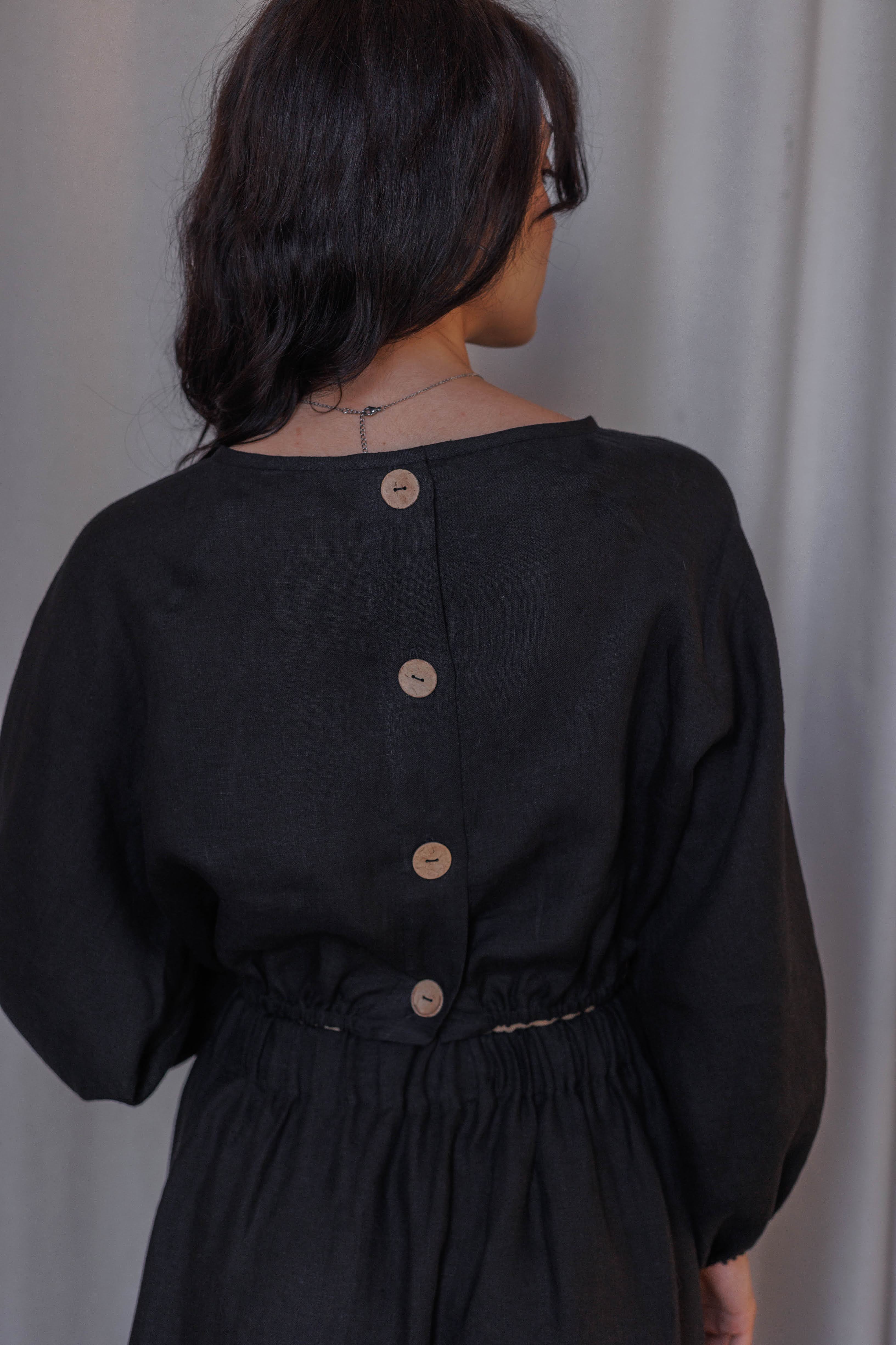 Light and breathable black linen blouse with puff sleeves, elasticated hem, and handmade details.