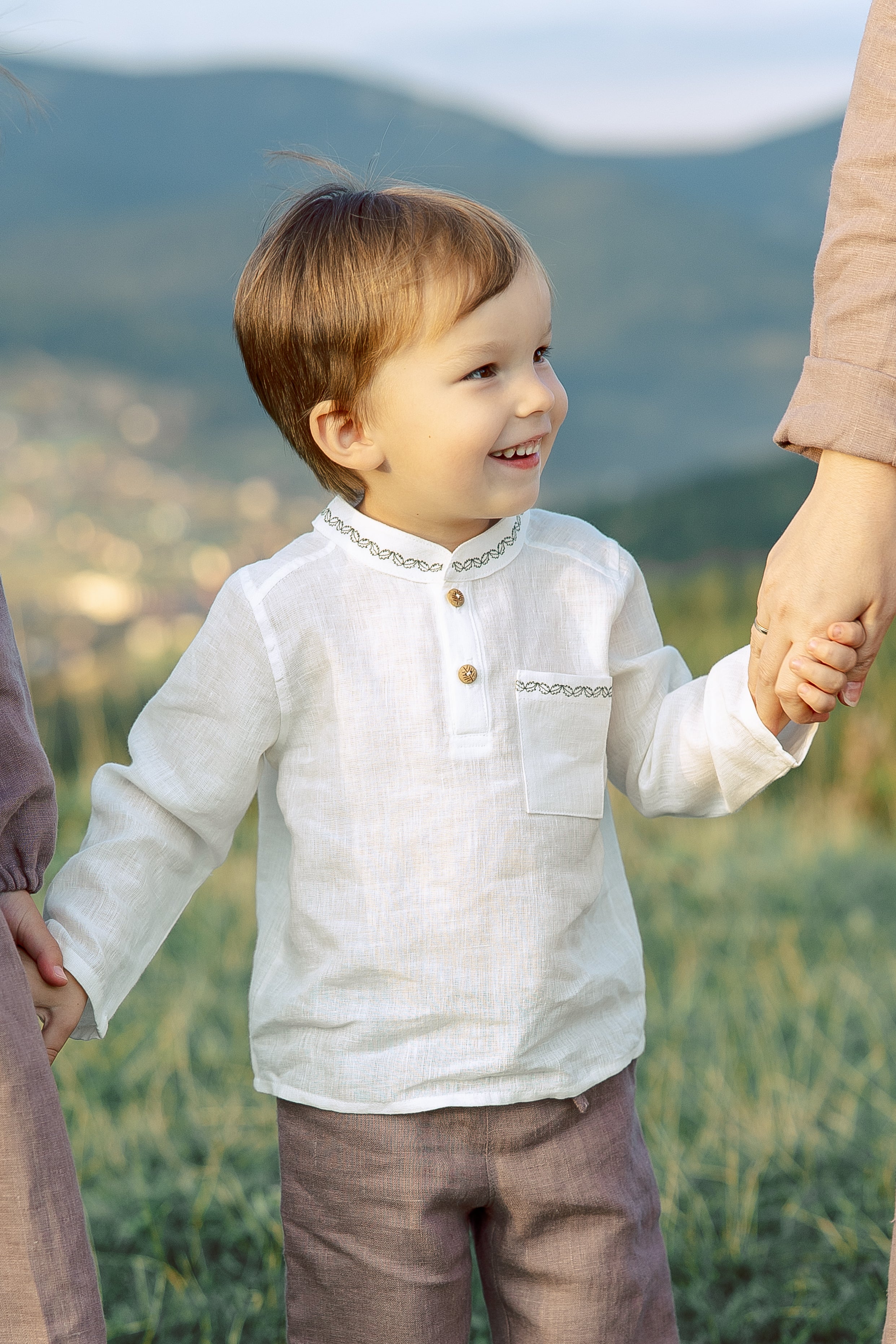 Boys’ white linen shirt with delicate dark green embroidery, handmade, soft 100% washed linen, perfect for special occasions.