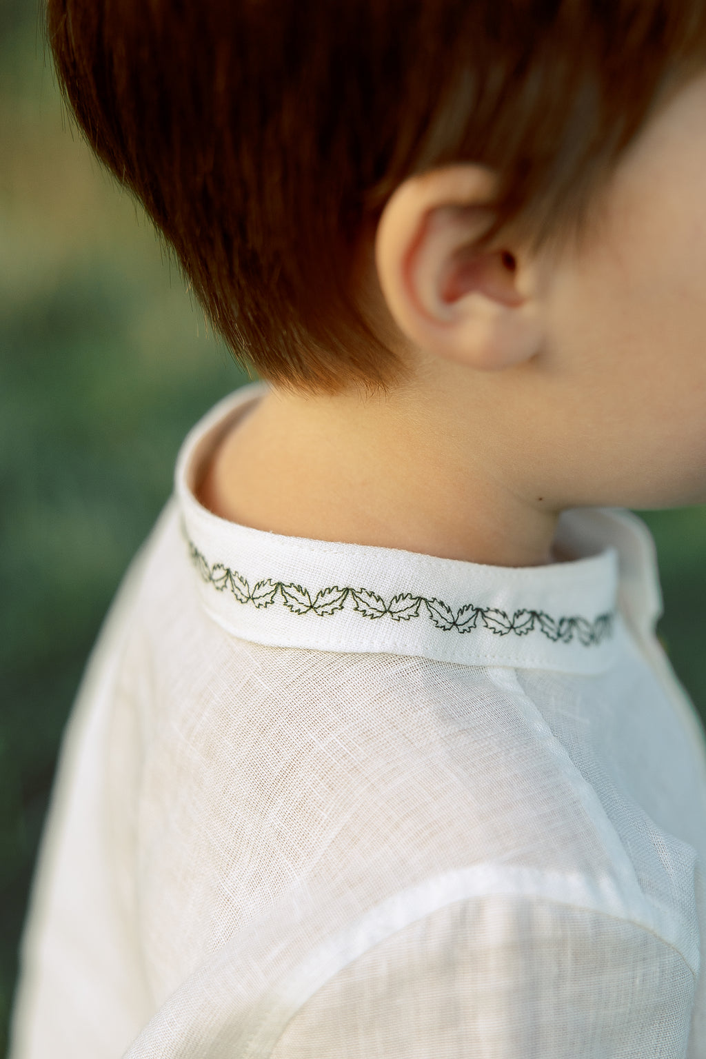 Handcrafted boys’ linen shirt, white color with festive green embroidery, ideal for birthdays, holidays, and family events.