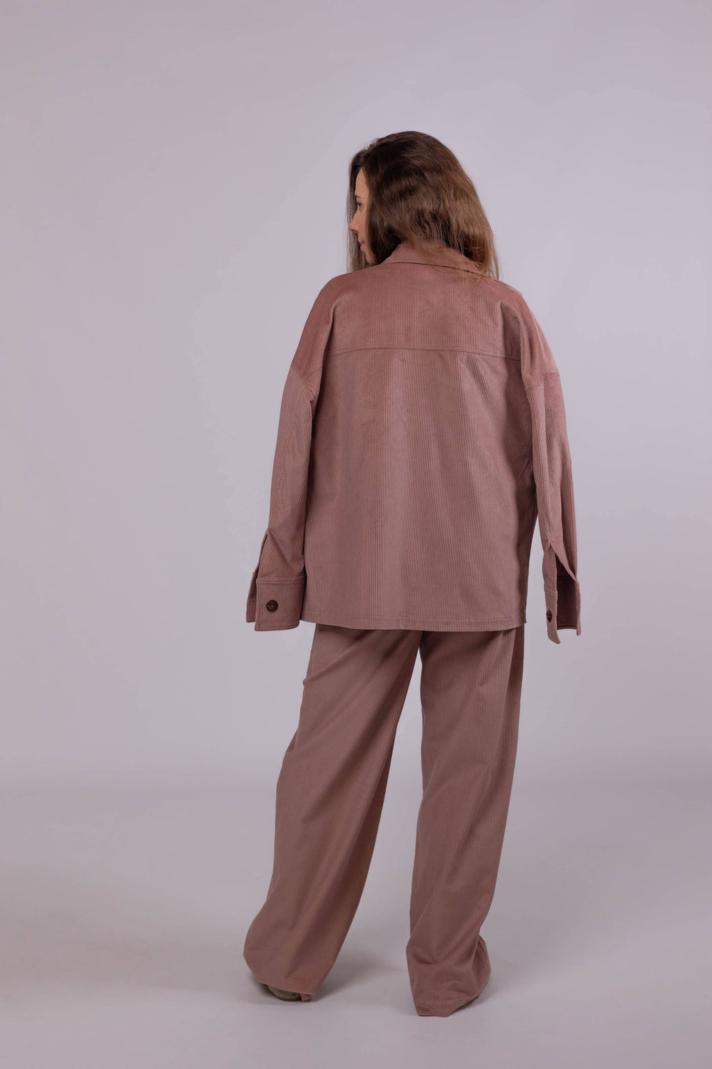 Oversized women’s corduroy shirt in powder pink, made from soft cotton fabric, styled as a light jacket.