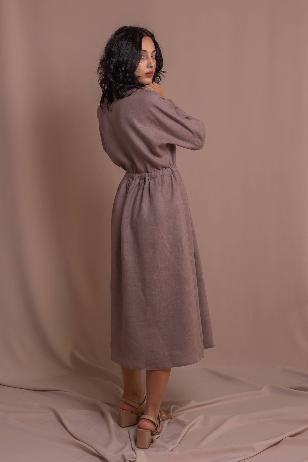 Woman wearing a wrap dress in 100% softened linen with long sleeves and drawstring waist