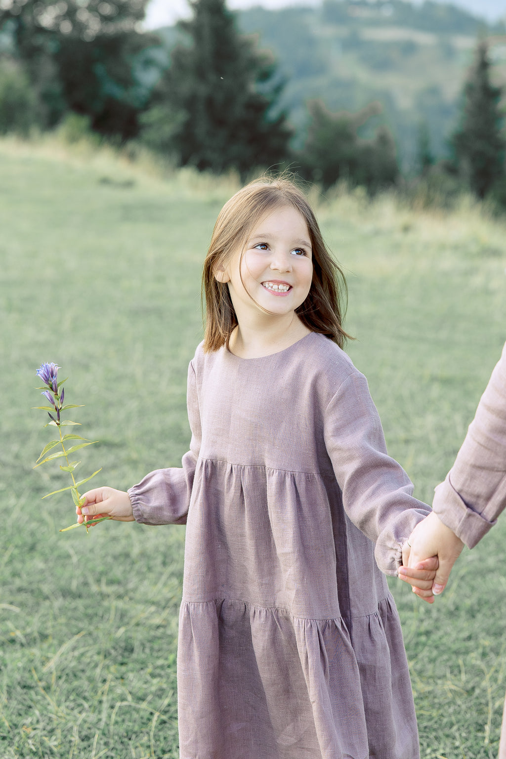 Girls’ linen dress with long puffed sleeves and two-tiered skirt in Purple Dove, back ties forming a bow.