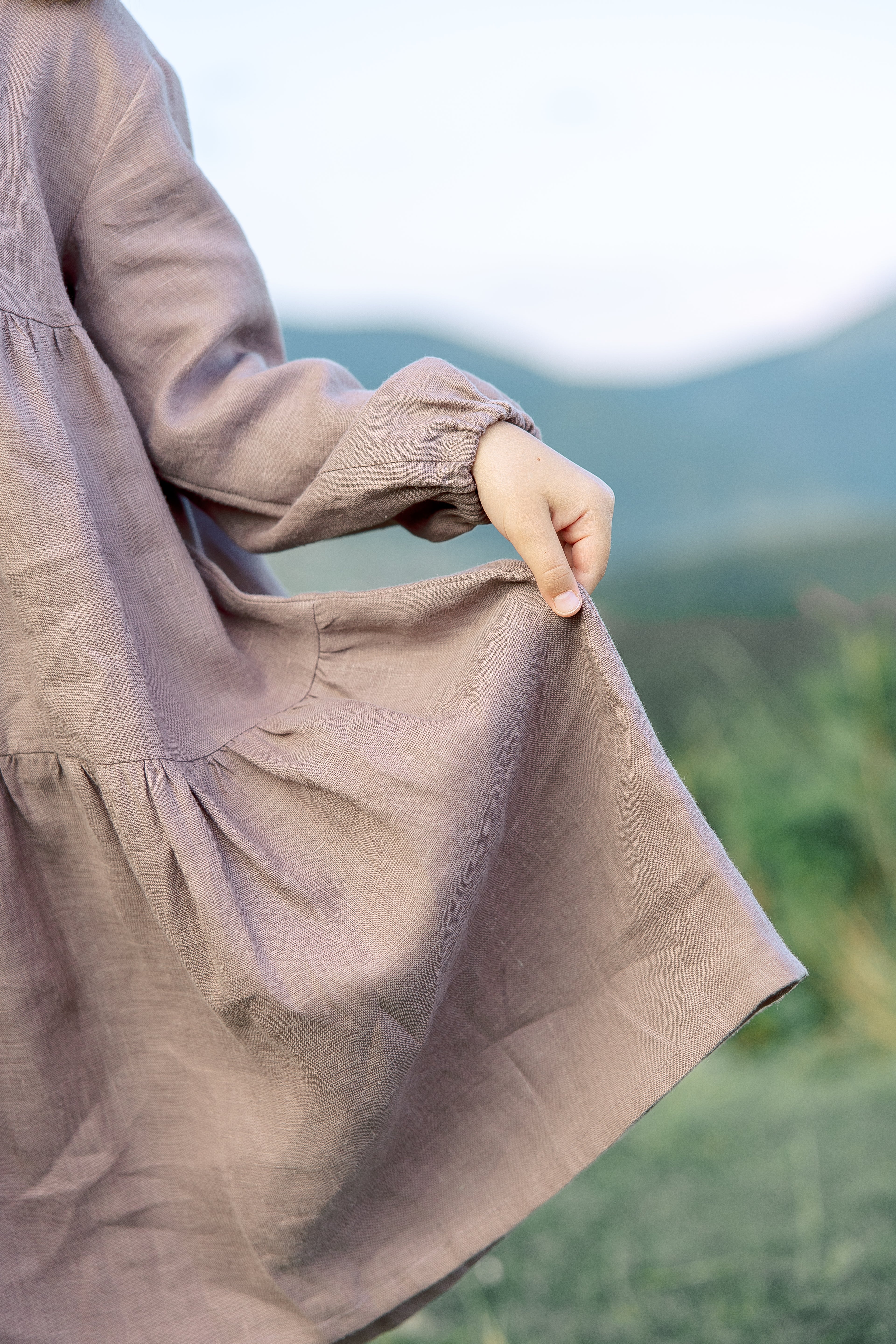 Charming handmade girls’ linen dress with elasticated puff sleeves, flowing skirt, and decorative bow at the back